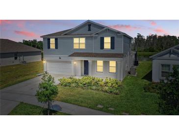 Charming two-story home with a manicured lawn, attached garage, and a welcoming entryway at 4307 Pebbles Throw Dr, Kissimmee, FL 34746
