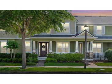 Charming two-story home with a covered front porch, manicured lawn, and a welcoming entrance featuring a decorative wreath at 8643 Coventry Park Way, Windermere, FL 34786