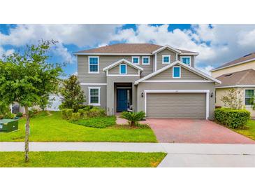 Charming two-story home featuring a well-manicured lawn, brick driveway, and a welcoming blue front door at 1317 Yorkdale Rd, Davenport, FL 33837