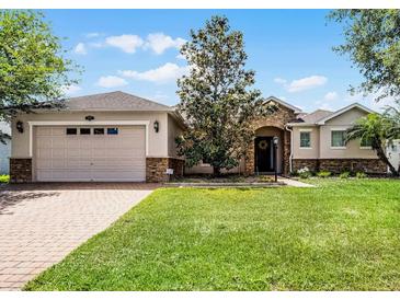Charming single-story home boasts a lush lawn, brick driveway, and stone accents for added curb appeal at 972 Bighorn St, Oviedo, FL 32765