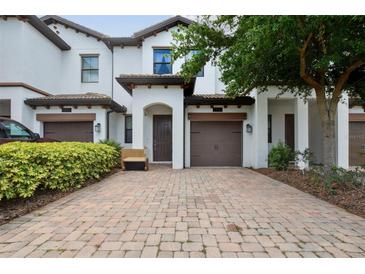 Inviting two-story townhome featuring a paver driveway and attached one-car garage at 1350 Royal St George Blvd, Davenport, FL 33896