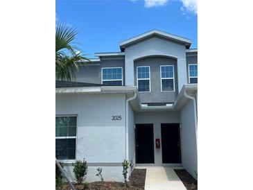 Two-story townhome featuring a modern facade, black front doors, and a well-maintained lawn at 2025 Claudia Ln # 2025, Kissimmee, FL 34741