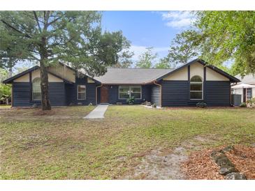 Charming home featuring a striking black exterior, a well-manicured lawn, and mature trees at 5340 Jones Rd, St Cloud, FL 34771