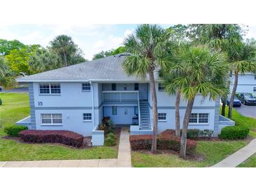 Charming two-story condo with tropical landscaping and exterior stairs leading to the second floor entrance at 576 Fairways Ln # M103, Ocala, FL 34472
