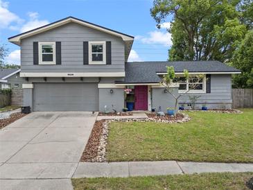 Charming two-story home with a well-maintained lawn, gray siding, and a vibrant pink front door at 1010 Chokecherry Dr, Winter Springs, FL 32708