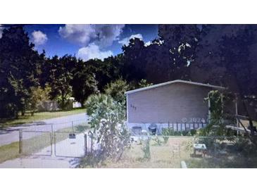 Modest home with neutral siding, surrounded by trees, and a chain-link fence in the front yard at 126 2Nd St, Orlando, FL 32824