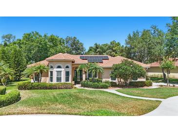 Charming home featuring a beautiful lawn, lush landscaping, and solar panels on the roof at 128 Lake Region Cir, Winter Haven, FL 33881