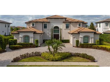 Elegant two-story home with a tile roof, manicured landscaping, and a circular driveway at 13125 Casabella Dr, Windermere, FL 34786