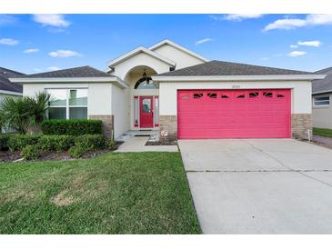Charming single-Gathering home showcasing a well-manicured lawn and inviting red garage door at 2535 Oneida Loop, Kissimmee, FL 34747