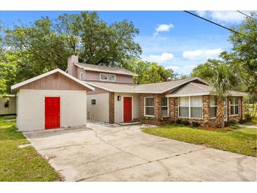 Charming two-story home with brick accents, mature trees, and a vibrant red front door at 3137 East St, Oviedo, FL 32765