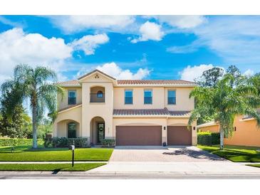 Stunning two-story home with a tile roof, paver driveway, palm trees, and lush landscaping at 4932 Eastlake Vista Dr, St Cloud, FL 34771