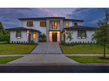 Stunning two-story home featuring a modern design with a paver driveway, manicured lawn and sophisticated front entrance at 5762 Emerington Cres, Orlando, FL 32819