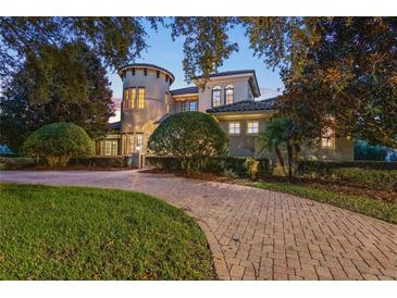 Elegant, stucco home featuring a circular driveway and tower design at 6143 Cartmel Ln, Windermere, FL 34786