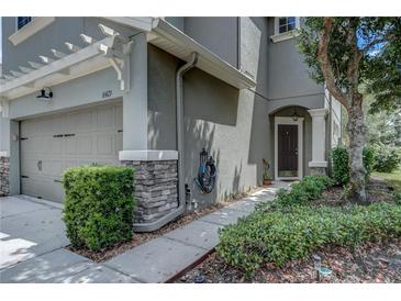 Inviting townhome features a well-maintained front yard with tidy landscaping and attached garage at 8419 Chamberlain Pl, Oviedo, FL 32765