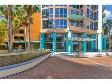 Inviting condo exterior featuring colorful architecture, lush palm trees, and a serene water fountain at 322 E Central Blvd # 1008, Orlando, FL 32801