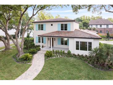 Charming two-story home featuring lush landscaping, light blue shutters, and a welcoming tile roof at 702 S Lake Adair Blvd, Orlando, FL 32804