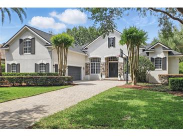 Stately two-story stucco home with a paver driveway, lush landscaping, and a basketball hoop above the garage at 11345 Preserve View Dr, Windermere, FL 34786