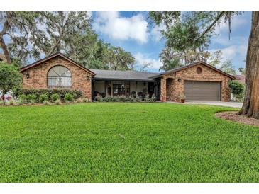 Well-maintained brick house featuring manicured landscaping, flowers, and a manicured lawn at 445 Songbird Way, Apopka, FL 32712