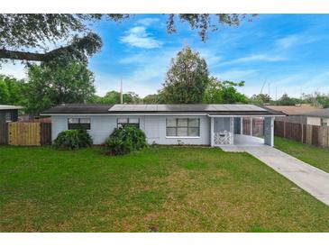 Charming single-story home with well-maintained lawn, carport, and solar panels under a bright blue sky at 6431 Greylynne St, Orlando, FL 32807