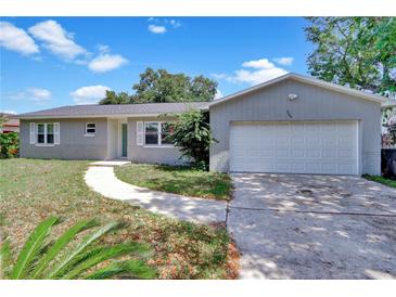Charming single-story home with a well-maintained lawn, paved walkway, and attached two-car garage at 7709 Pine Hollow Ct, Orlando, FL 32822