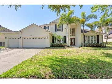 Stately two-story home with a three-car garage, manicured lawn, and mature landscaping with palm trees at 8208 Westminster Abbey Blvd, Orlando, FL 32835