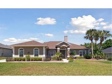 Charming single-story home featuring a stone entrance, manicured lawn, and lush landscaping with palm trees at 564 Dowling Cir, Lady Lake, FL 32159