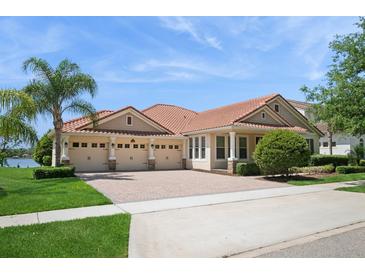 Elegant home featuring a three-car garage, red tile roof, and well-maintained landscaping with a palm tree at 15698 Marina Bay Dr, Winter Garden, FL 34787