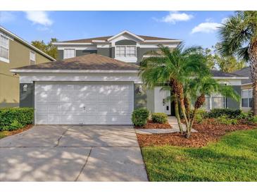 Inviting two-story home with a manicured lawn, palm trees, and a two-car garage at 213 Hideaway Beach Ln, Kissimmee, FL 34746