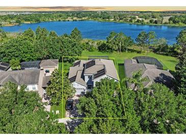 Aerial view of a two-story home featuring solar panels and a well-manicured lawn near a serene lake at 6152 Meriwether, Winter Garden, FL 34787