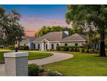 Charming single-story home featuring a circular driveway, well-manicured lawn, and lush landscaping at 8368 Rambling River Dr, Sanford, FL 32771