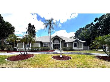 Beautiful single-story home featuring manicured landscaping and a circular driveway with a charming water fountain feature at 8935 Jonathan Manor Dr, Orlando, FL 32819