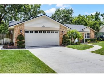 Two car garage with a lush green lawn and landscaped shrubs at 1013 Glensprings Ave, Winter Garden, FL 34787