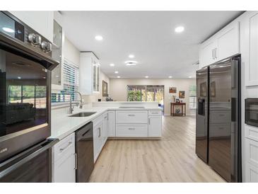 Open kitchen with modern appliances, white cabinets, and eat-in bar at 110 Tedworth Ct, Longwood, FL 32779