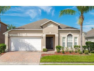 Charming single-story home with a well-manicured lawn, brick driveway, and attached two-car garage at 16843 Cedar Run Dr, Orlando, FL 32828