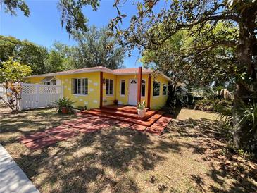 Charming yellow home featuring a cozy front porch, stone walkway, and lush, mature trees at 1236 Illinois St, Orlando, FL 32803