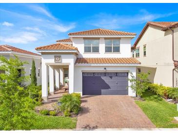 Charming two-story home featuring a tile roof, brick driveway, manicured landscaping, and a covered front entrance at 13543 Abberwick Dr, Orlando, FL 32832