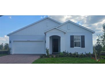 Charming single-story home featuring a two-car garage, well-manicured lawn, and elegant architectural details at 14599 Crestavista Dr, Clermont, FL 34714