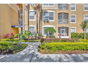 Attractive condo exterior featuring tan stucco, verdant landscaping, and a walkway at 2781 Almaton Loop # 105, Kissimmee, FL 34747