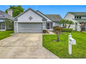 Charming home features a well-manicured lawn, mature landscaping, and a two-car garage at 2885 Autumn Green Dr, Orlando, FL 32822