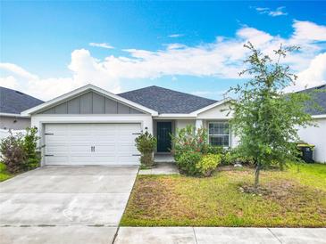 Charming one-story home features a two-car garage, manicured lawn, and beautiful landscaping at 408 Lily Ln, Davenport, FL 33837
