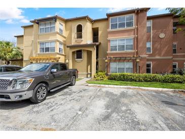 Inviting multi-story condo building featuring manicured landscaping, pergola and ample parking spaces on a sunny day at 5156 Conroy Rd # 1124, Orlando, FL 32811