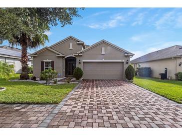 Charming single-story home featuring a brick driveway, well-maintained landscaping, and a two-car garage at 528 Bridgeford Crossing Blvd, Davenport, FL 33837