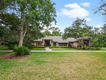 Charming single-story home with a lush lawn, mature trees, and brick facade, providing great curb appeal at 554 Estates Pl, Longwood, FL 32779