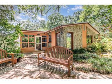 Charming home featuring stone accents and a cozy patio with a wooden bench at 1860 Ne 62Nd St, Ocala, FL 34479