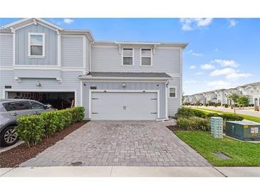 Charming townhouse featuring light-blue siding, a two-car garage, and a well-maintained brick-paved driveway at 2934 Title St, Kissimmee, FL 34746
