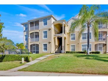 Condo building featuring tan siding, screened balconies, and well-maintained landscaping at 8107 Coconut Palm Way # 102, Kissimmee, FL 34747