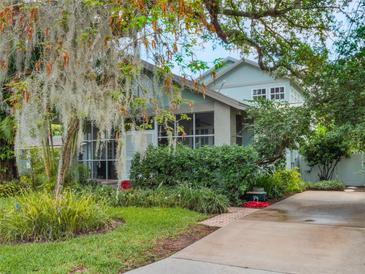 Charming two-story home with screened porch, lush landscaping, and a concrete driveway leading up to the residence at 811 Laurel Ave, Orlando, FL 32803
