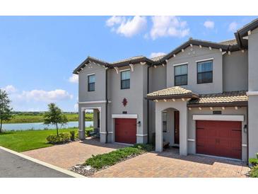 Charming townhome exterior with brick driveway, lake view, and red garage door at 8549 Zoeller Hills Dr, Davenport, FL 33896