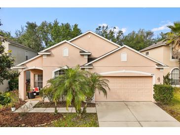 Charming, peach-colored two-story home with a well-manicured lawn and a two car garage at 14556 Unbridled Dr, Orlando, FL 32826
