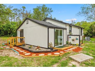 Charming home exterior with sliding glass door, wood accents, and beautiful landscaping at 151 Naranja Rd, Debary, FL 32713